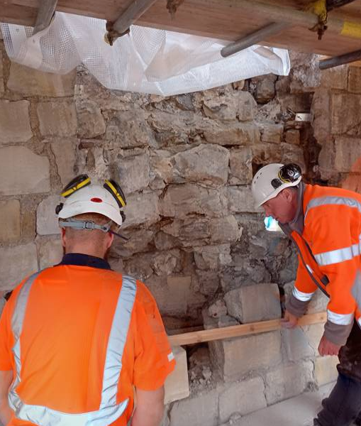Stonemasons fitting new stones to city wall